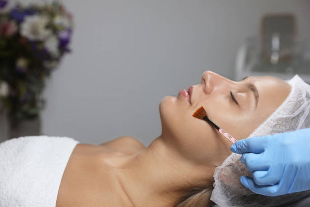 Cosmetologist applying chemical peel product on client's face in salon - Photo, Image