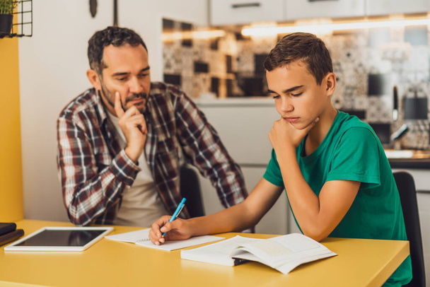 Vader helpt zijn zoon met leren. Ze doen samen huiswerk.. - Foto, afbeelding