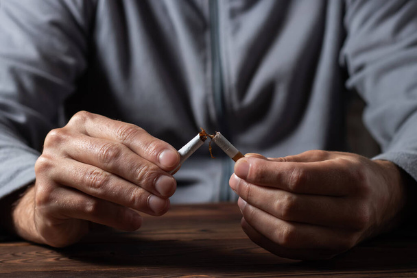 Zigarette. Konzept zum Weltnichtrauchertag. Hört auf, Zigaretten zu rauchen. Mann in Nahaufnahme hält kaputte Zigarette in Händen. - Foto, Bild