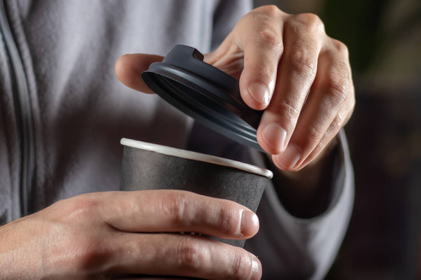 Чоловік відкриває паперову чашку кави крупним планом
. - Фото, зображення