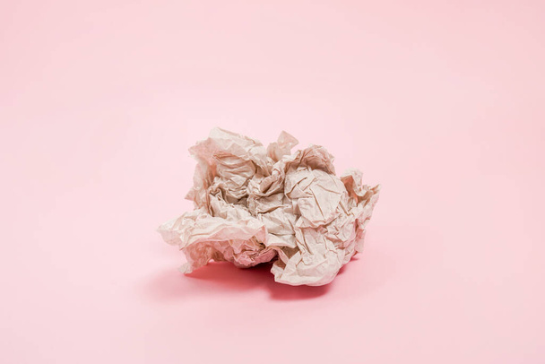 Crumpled paper ball laying on pink background - Фото, изображение