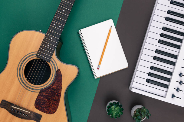 Akustikgitarre, Notenschlüssel und ein leerer Notizblock auf farbigem Hintergrund, Draufsicht. - Foto, Bild