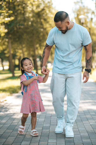 Time together. Little girl with backpack and her father in the park - 写真・画像
