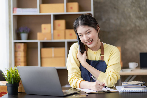 アジアの女性は電話で注文を取るオンライン販売、配達、マーケティング。自宅で働いている間、デジタルノートパソコンを持つ若いアジアの起業家を興奮させました。中小企業スタートアップ｜中小企業 - 写真・画像