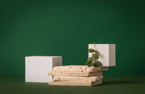 Product presentation mockup scene made with travertine tiles, white cubes and eucalyptus branch on a green background. Front view, copy space. - Photo, image