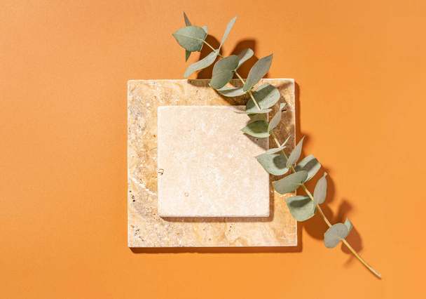 Travertine tiles. Empty square mockup template for product presentation made with natural travertine and eucalyptus on a yellow background. Flat lay with copy space. Top view. - Photo, image