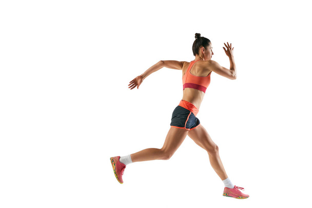 Dynamisch portret van professionele vrouwelijke atleet, hardloper of jogger die zomersportkleding draagt die geïsoleerd op een witte achtergrond loopt. Sport, fitness, energie, bewegingsconcept - Foto, afbeelding