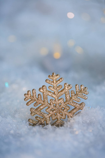 Christmas golden snowflake on a blue snow. Blurred background with beautiful bokeh. Shallow depth of field. Toned image. Copy space. Airy atmosphere. Art photography. Soft focus. Close-up. - Фото, изображение