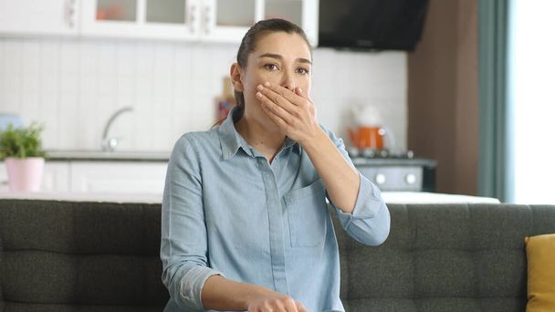 Uma jovem que está doente está a tossir. Uma jovem de 30 anos com dificuldade em respirar na sala de estar de sua casa. Falta de ar, asma, dificuldade em respirar. Sintomas de vírus Corona. - Foto, Imagem