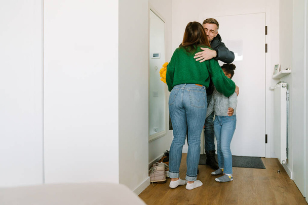 Happy adoptive sisters with mother meeting at the door their father who came home - Photo, Image