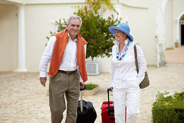 Venimos aquí todos los años. una pareja de ancianos tirando de sus maletas detrás de ellos mientras están de vacaciones - Foto, Imagen