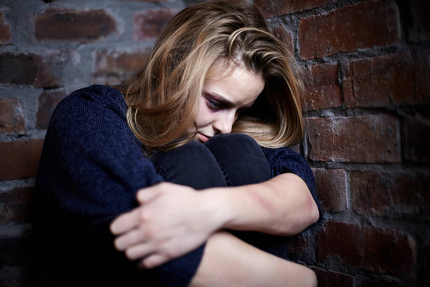 Złamany i pobity. Wykorzystywana młoda kobieta przytulona i kucąca w kącie - Zdjęcie, obraz