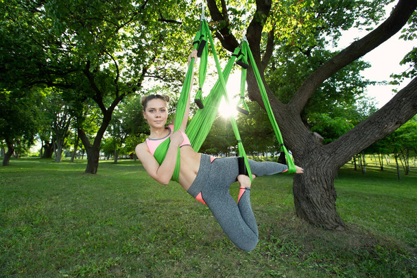 Anti-gravity Yoga, woman doing yoga exercises in the park - Foto, Imagen