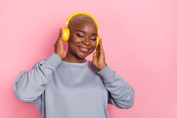 Portrait of positive adorable girl closed eyes hands touch headphones enjoy new single isolated on pink color background. - Φωτογραφία, εικόνα