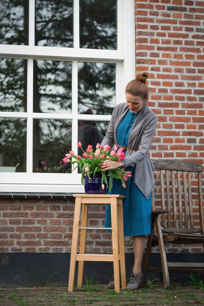 florist. girl makes a bouquet with pink tulips near with a traditional Dutch house. The Netherland - Foto, Imagen