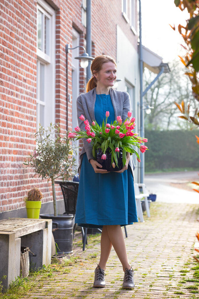 smiling happy girl holding a vase with pink tulips near with a traditional Dutch house. The Netherland - Φωτογραφία, εικόνα