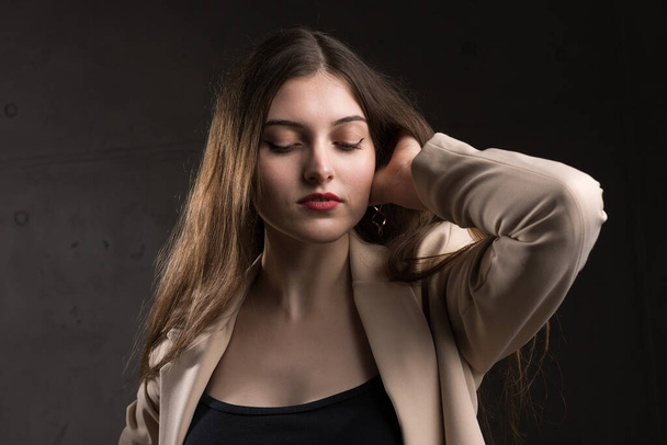 Portrait of a young brunette with long hair in the studio. Dramatic photo in dark colors. - Photo, image