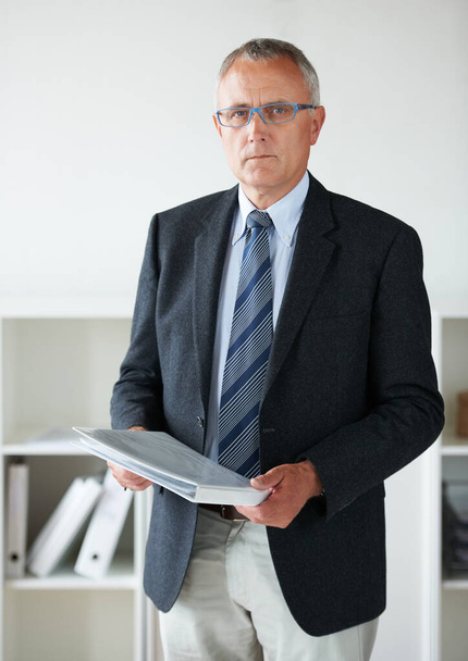 Hes worked hard to get where he is. Portrait of a senior businessman standing in his office holding documents - Photo, Image