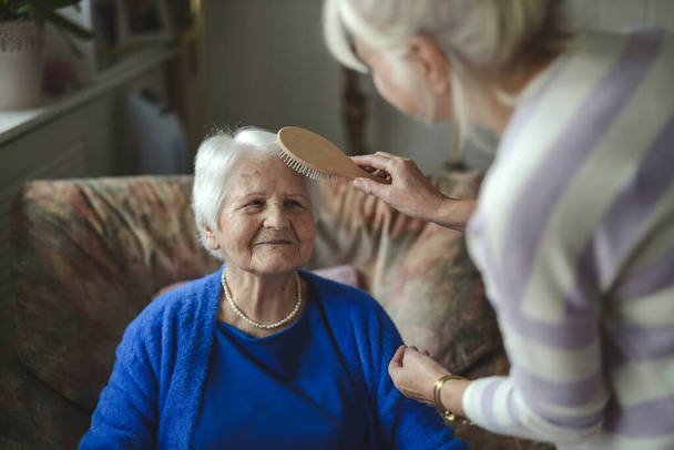 Woman combing hair of elderly mother  - Fotoğraf, Görsel