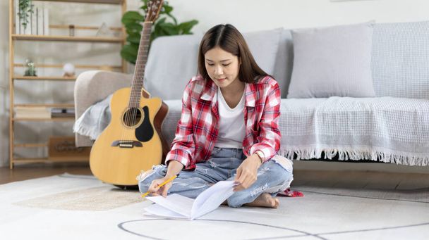 Ázsiai nő specializálódott zene komponálja a dalszöveget és dallamot a nyitó egy új kislemez, A képzelet és a koncentráció létrehozására zene, akusztikus gitár, Létrehozása zenei jegyzetek. - Fotó, kép