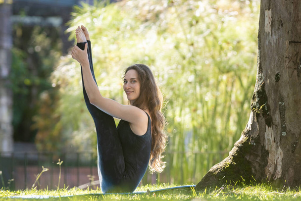 Una donna fa yoga nel parco e guarda nella telecamera. Mid shot - Foto, immagini
