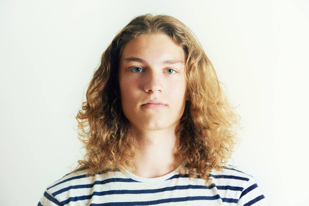 Hes got his own look. Young man with curly long hair standing by himself - Foto, Bild