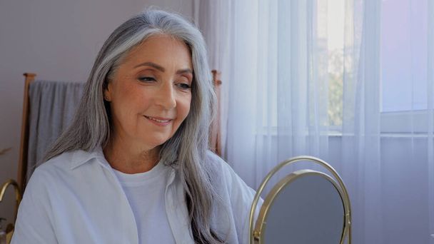 Caucasico sorridente bella vecchia signora anziana maturo anziano modello donna con capelli grigi femmina guardando specchio riflesso sorriso guardare rughe viso pelle liscia naturale bellezza del viso carnagione - Foto, immagini