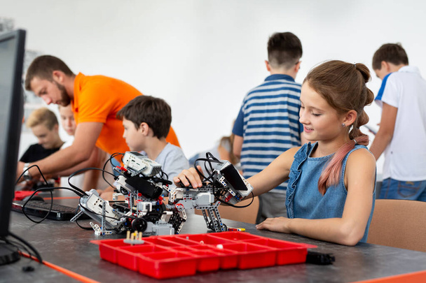 Education, children, technology, science and people concept - group of happy kids with laptop computer building robots at robotics school lesson - Fotoğraf, Görsel