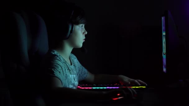 Menino olha para monitor e joga jogo cibernético computador à noite.  - Filmagem, Vídeo