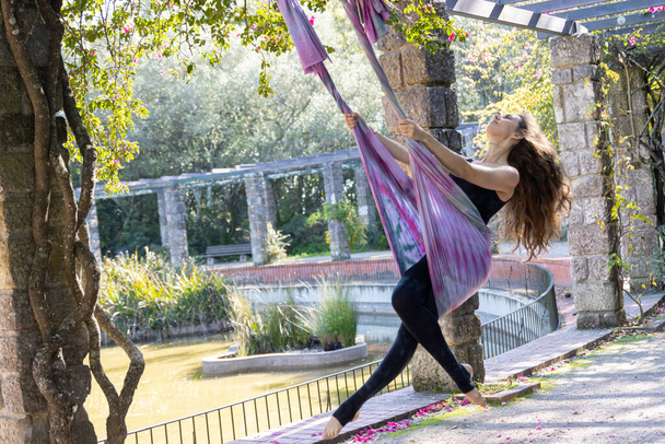 Una mujer que hace yoga aéreo utiliza la hamaca como oscilación. Mid shot - Foto, Imagen