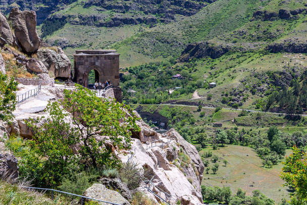 Здание колокольни в пещерном монастырском комплексе Вардзия в Грузии, горный склон с резными древними пещерами, долина реки Кура на заднем плане. - Фото, изображение