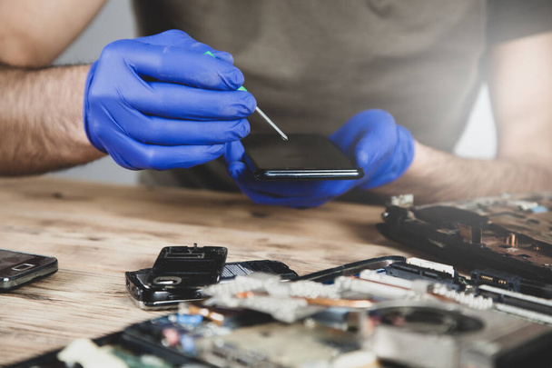 man worker to repair smart phone on the wooden table - Φωτογραφία, εικόνα