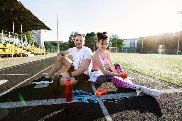 Man and a woman sit in the stadium and laugh. Outdoor sports activities - Fotografie, Obrázek