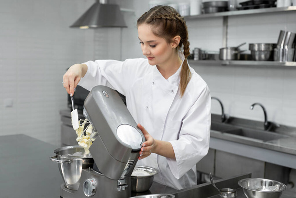 Pastry chef in the kitchen adds sugar to the kitchen machine, mixer. - Fotoğraf, Görsel