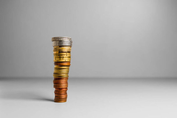 High stack of coins with free space for text on gray background. Coins are arranged from smaller to larger. - Photo, Image