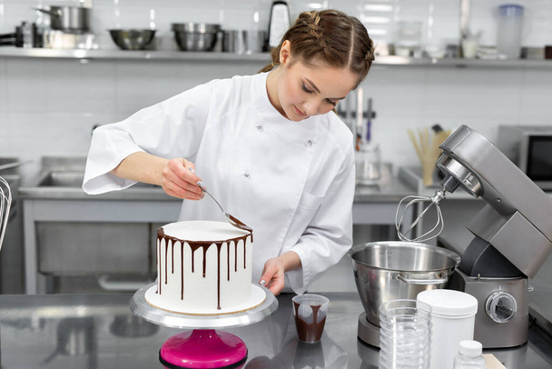 Pastry chef decorates the cake with chocolate streaks. - Valokuva, kuva
