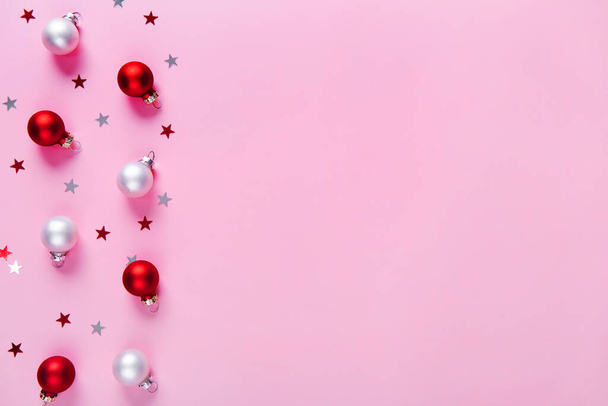 Modello di vacanza creativa. Sfondo natalizio di bagattelle rosse e bianche su sfondo rosa. Piatto. Ricevuto. Composizione minima. - Foto, immagini