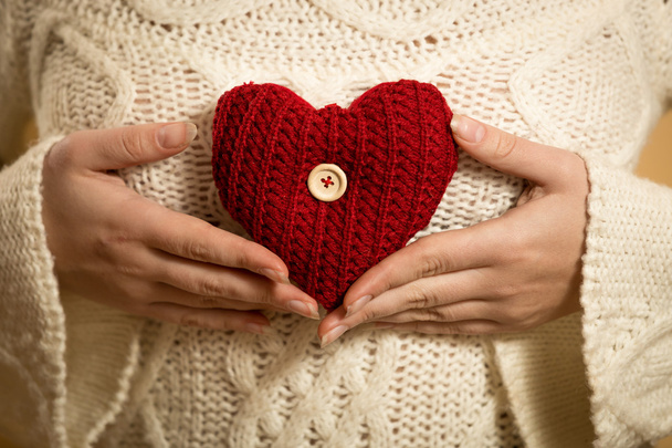γυναίκα που ποζάρει με κόκκινη καρδιά σε λευκό πουλόβερ - Φωτογραφία, εικόνα