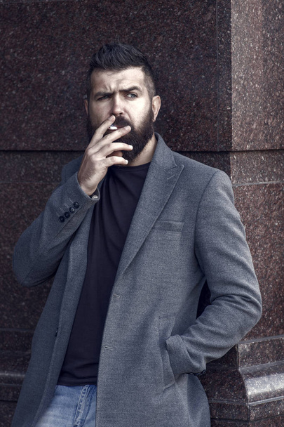 male bad habits. addiction. casual fashion in modern life. confident and handsome brutal man. smoke. hipster with beard smoking cigarette. brutal caucasian hipster with moustache. Hip and stylish. - Фото, зображення