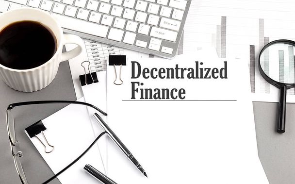 Finanza decentralizzata su carta con lente d'ingrandimento, caffè e tastiera su sfondo grigio - Foto, immagini