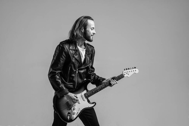 bearded rock musician playing electric guitar in leather jacket, musician. - Photo, image