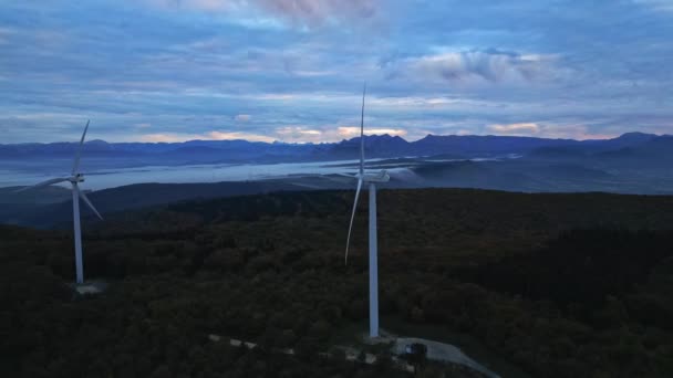 Turbinas eólicas en las montañas durante el amanecer y espesa niebla matutina en el valle. Parque eólico que produce energía verde. - Metraje, vídeo