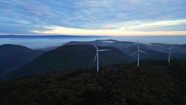 Szélturbinák a hegyekben napkeltekor és sűrű reggeli köd a völgyben. Zöld energiát termelő szélerőmű-gazdaság. - Felvétel, videó