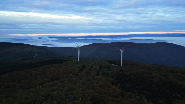 日の出と谷の厚さの朝の霧の間に山の中で風力タービン。緑のエネルギーを生産する風力発電所. - 映像、動画