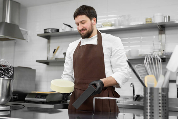 Man pastry chef takes out a frozen mousse cake from a silicone mold. - Valokuva, kuva