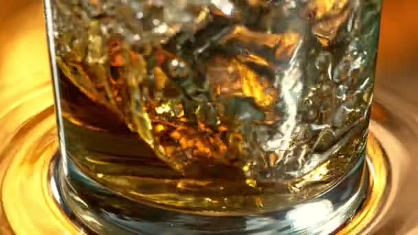 Super Slow Motion Detail Shot of Ice Cube putoaa viskiin 1000 fps nopeudella. Kuvattu High Speed Cinema Camera 4K. - Materiaali, video