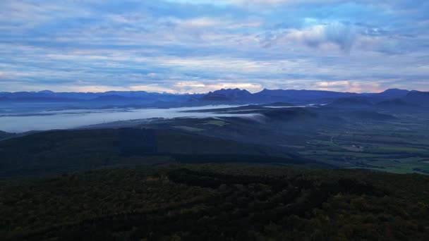 The morning mist trapped in the valley flows to the other side of the mountain. Panoramic view of the French Alps in the morning. Wind power station in thick fog in the distance - Footage, Video