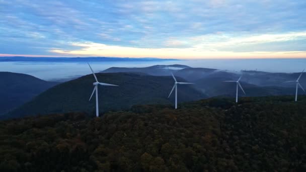 Wind turbines in the mountains during sunrise and thick morning fog in the valley. Wind farm producing green energy. - Footage, Video