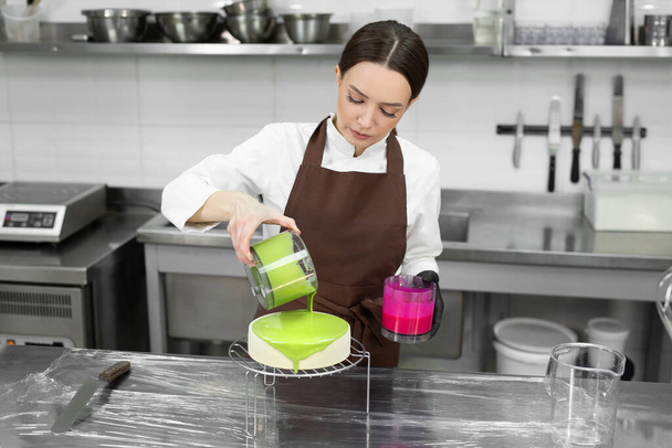 Female pastry chef decorates a mousse cake with a mirror glaze. - 写真・画像