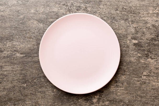 Top view of empty pink plate on cement background. Empty space for your design. - Photo, image